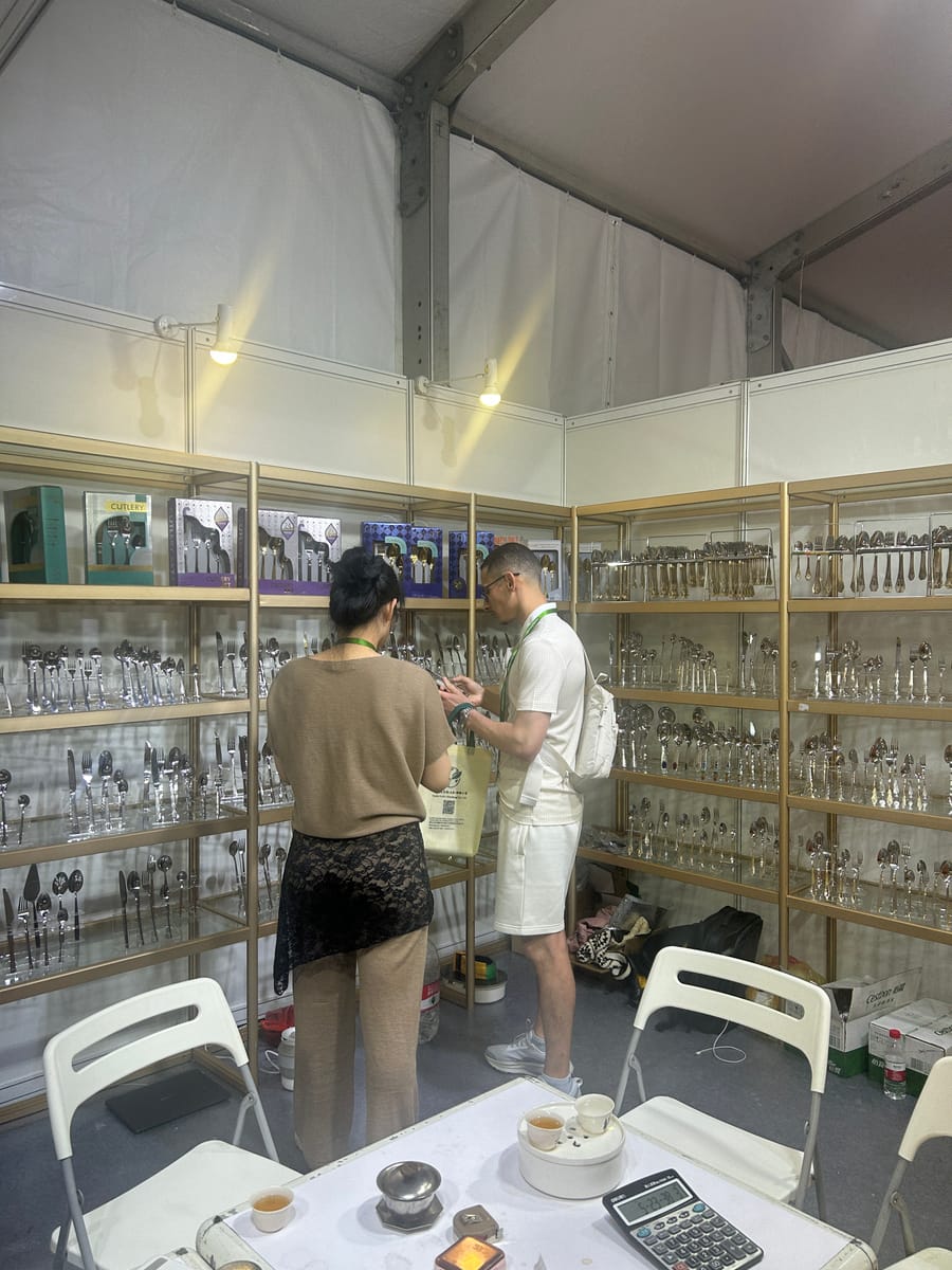 Buyers examining cutlery sets at exhibition booth